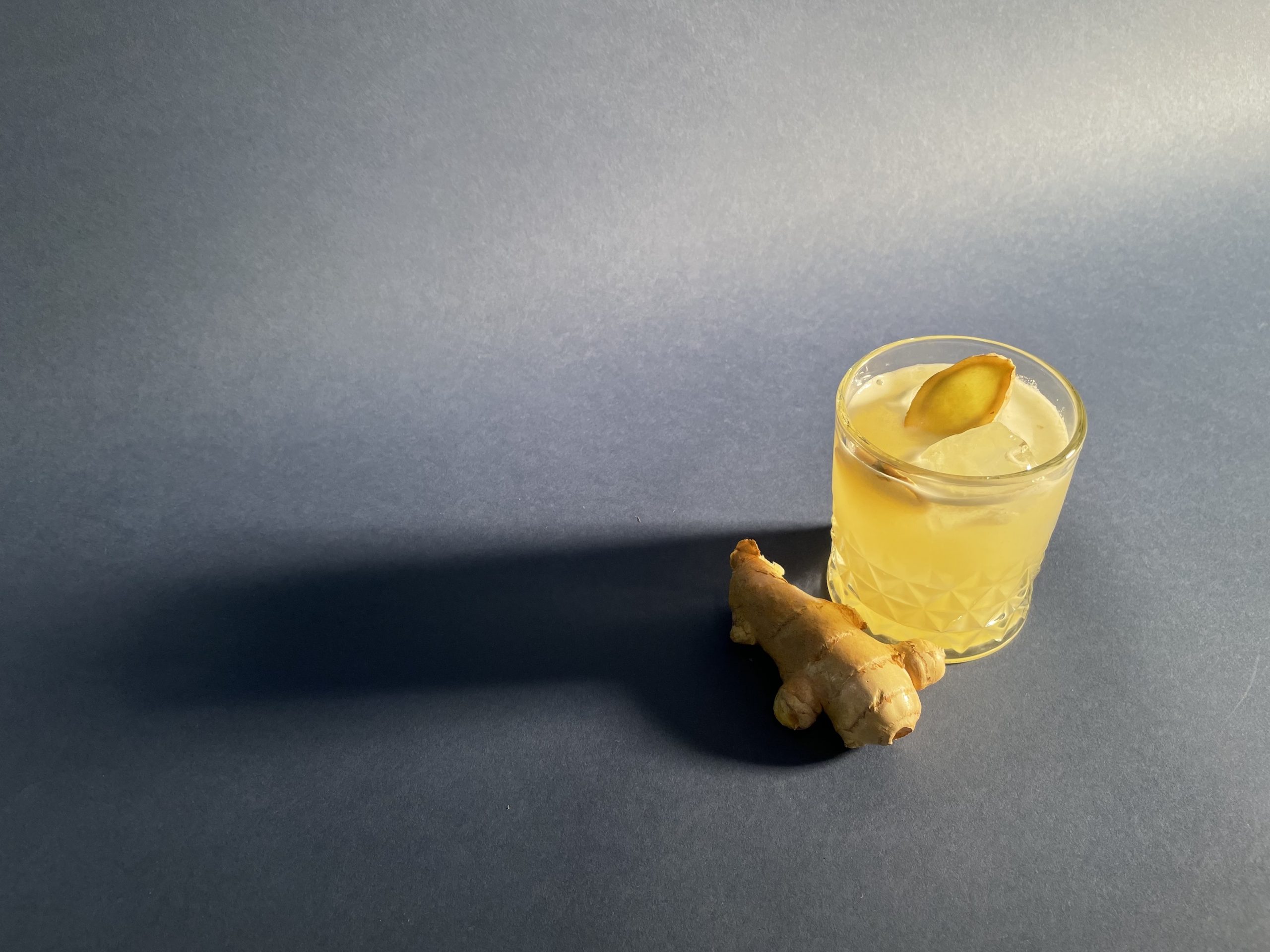 Das Bild zeigt einen Longdrink Mosvow Mule nach Rezept zubereitet, daneben liegt ein Stück Ingwer.